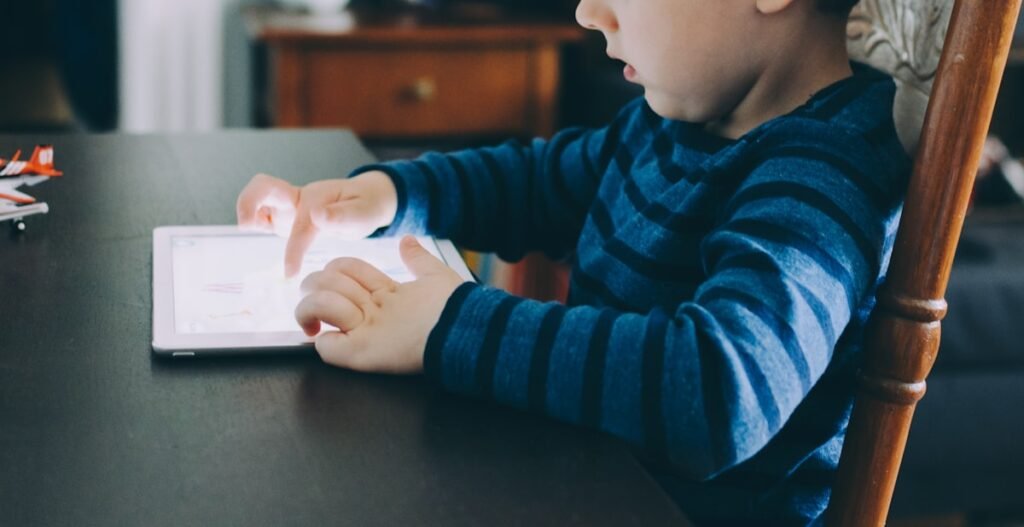 Enfant assis à une table utilisant une tablette