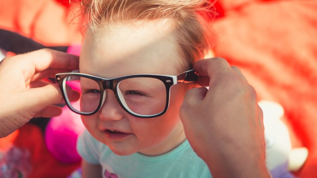 Jeune enfant souriant portant des lunettes à monture noire